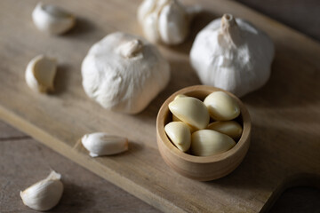 Obraz na płótnie Canvas Seasoned Garlic and Herbs for Delicious Home Cooking. Fresh garlic and a variety of aromatic herbs are beautifully arranged on a wooden table, evoking the natural flavors and fragrances.