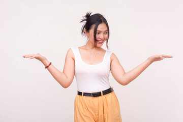 A happy young Asian woman with braces casually shrugging while looking to the right at her palm. Isolated on a white background.