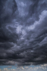 Epic Dramatic storm dark grey cumulus rain clouds against blue sky background texture, thunderstorm