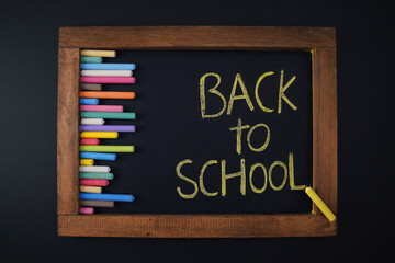 back to school education concept wallpaper, chalkboard with colorful chalks and text on blackboard, dark background design