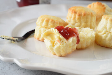a plate of butter scones served with butter and strawberry jam 