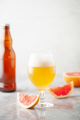 Boozy Refresing Cold Grapefruit Beer in a Pint Glass and Bottle on table. Copy space