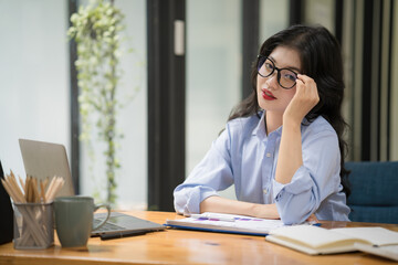 An attractive Asian businesswoman wearing eyeglasses thoughtful thinking about work in a new project.