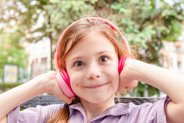 Cute child girl with headphones listening to music outdoor
