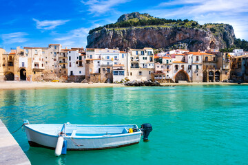 Fishing boat in Cefalu, medieval town on Sicily island, Italy. Seashore village with beach and clear turquoise water of Tyrrhenian sea, surrounded with mountains. Popular tourist attraction