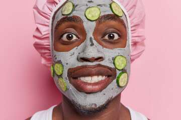 Facial treatment and cosmetology concept. Close up shot of cheerful dark skinned man applies facial...