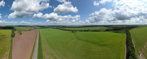 Aerial view. Russian nature in summer. Blue sky white clouds. Road to the distance.