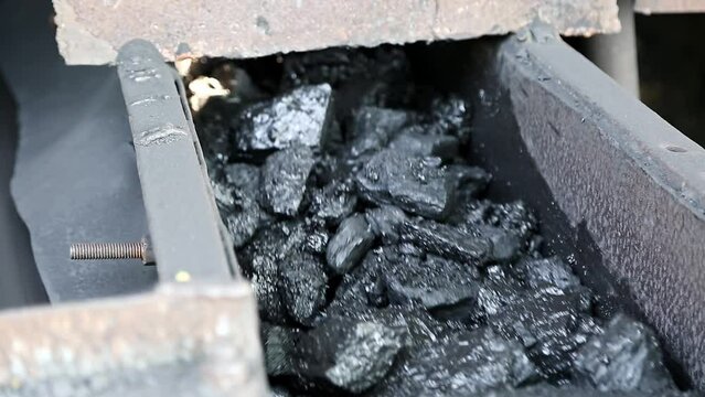 Closeup of charcoal or bituminous coal moving on a roller belt conveyor machine