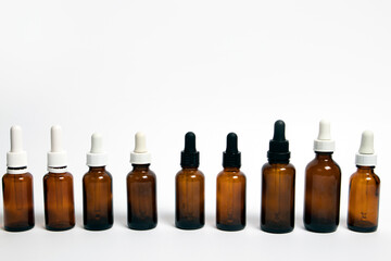 Glass dropper bottles with a pipette on white background