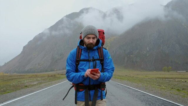 Travel man with phone to search gps location on journey adventure in contryside road. Vacation, holiday or happy walking tourist on internet for roadmaps or directions online. Beautiful foggy