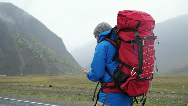 Travel man with phone to search gps location on journey adventure in contryside road. Vacation, holiday or happy walking tourist on internet for roadmaps or directions online. Beautiful foggy