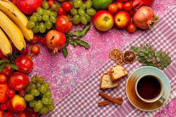 Naklejka na ściany i meble top view fresh fruit composition colorful fruits with cup of tea and cakes on the pink background fruit fresh mellow color ripe