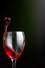 Splash of red wine in a glass on a black background