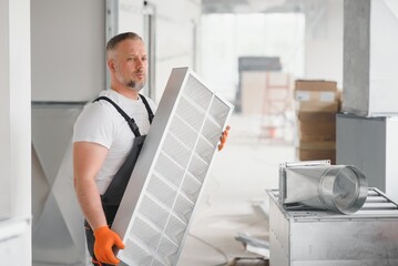 Worker holding air filter for installing in the office ventilation system. Purity of the air concept.