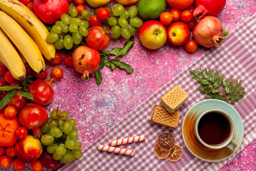 Obraz na płótnie Canvas top view fresh fruit composition colorful fruits with cup of tea and waffles on pink background fruit fresh mellow color ripe
