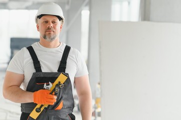 A man with a beard in a helmet and work clothes. Portrait of a worker in workwear with copy space.