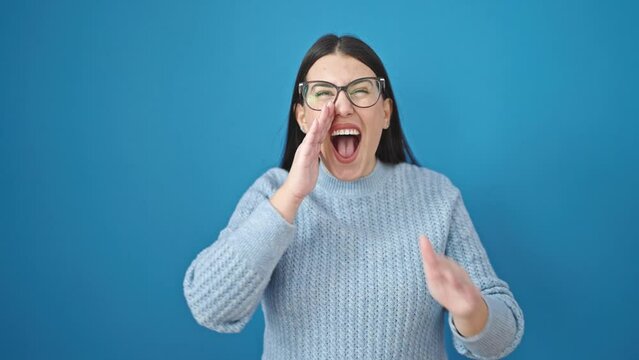 Young hispanic woman standing with winner expression shouting over isolated blue background