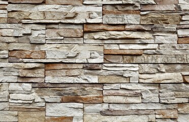 Stone cladding wall made of  striped stacked slabs of  gray and brown rocks. Panels for exterior....