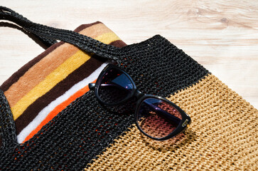 Women's bag with a towel and sunglasses on the table.