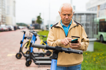 Elderly man rents an electric scooter using mobile phone