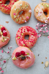 pink glazed donuts with raspberries, pistachios and flowers