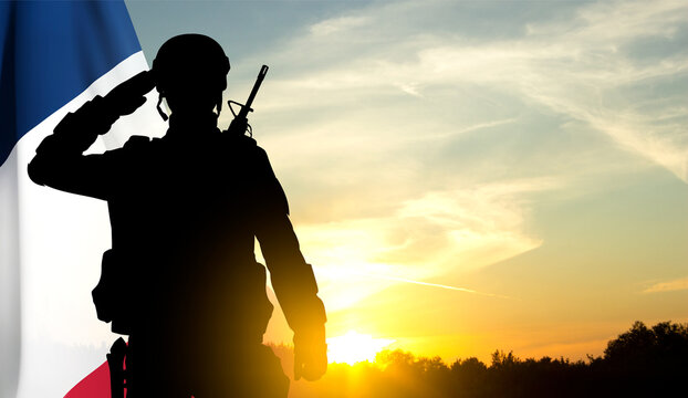 Silhouette of French soldier on background of sunset and French flag