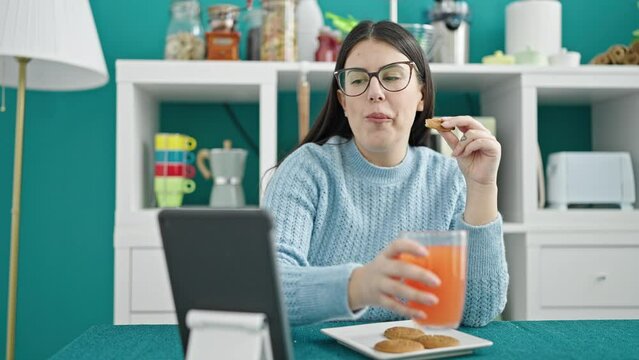 Young hispanic woman using tablet having breakfast at dinning room