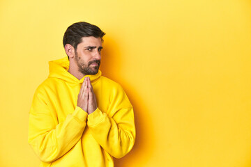 Man in yellow hoodie, monochrome studio backdrop making up plan in mind, setting up an idea.