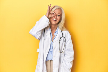 Middle-aged Caucasian female doctor on yellow studio backdrop Middle-aged Caucasian female doctor...
