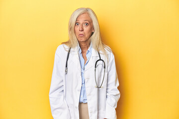 Middle-aged Caucasian female doctor on yellow studio backdrop Middle-aged Caucasian female doctor...