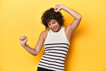 Caucasian curly-haired woman in white tank-top dancing and having fun.
