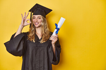 Young caucasian woman wearing a graduation robe holding a diploma Ycheerful and confident showing...