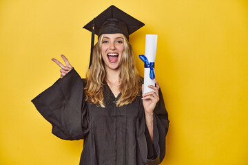 Young caucasian woman wearing a graduation robe holding a diploma Yjoyful and carefree showing a...