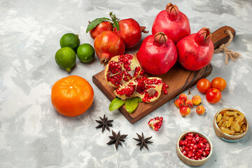 front view fresh red pomegranates with tangerines and plums on the light-white desk fruits fresh mellow ripe tree