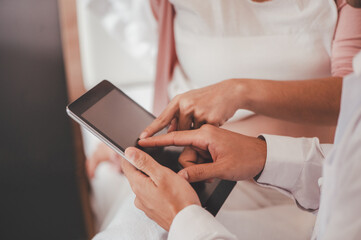 Concept Motherhood and Pregnant, Prenatal care and pregnancy. Male doctor checkup list the baby ultrasound picture on tablet to pregnant woman sitting on the bed.