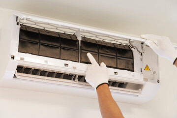 An air conditioner technician is inspecting the air conditioner. A large amount of dust settles in the air filter.