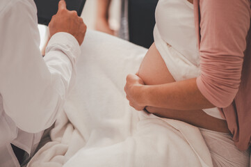 Obraz na płótnie Canvas Concept Motherhood and Pregnant, Prenatal care and pregnancy. Male doctor checkup list the baby ultrasound picture on tablet to pregnant woman sitting on the bed.