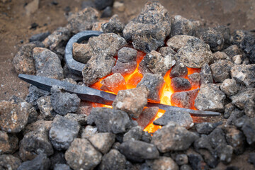 Piece of wrought iron between glowing coals in a forge