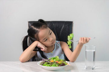 Obraz na płótnie Canvas Little asian cute girl refuses to eat healthy vegetables.Nutrition & healthy eating habits for kids concept.Children do not like to eat vegetables.