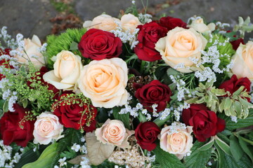 Rosen in Rot und Lachs in Trauerkranz nach Beerdigung auf dem Friedhof