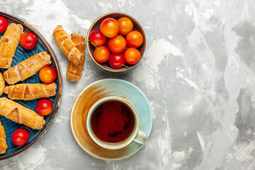 top view delicious sweet bagels with sour plums and tea on light white desk pastry cake bake biscuit sweet sugar fruit