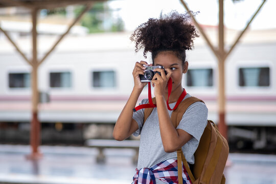 Young Asian African woman traveler with backpack in the railway train, traveler girl walking stand sit waiting take a picture on railway platform