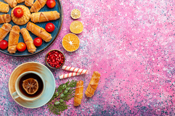 top view sweet delicious bagels inside tray with plums and cup of tea on light pink desk cake biscuit cookies sweet sugar pie