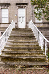Steps with cast iron railings lead up to a whiet door on an old building.
