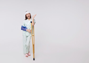 Asian woman wearing a patient gown put on a cast Use a crutch to walk due to accidental injury...