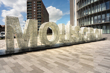 A big sign with the name of the city Mouscron, Moeskroen België.  