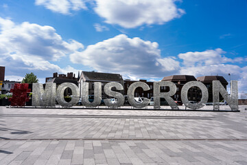 A big sign with the name of the city Mouscron, Moeskroen België.  