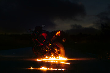 Motorcycle stands next to a burning puddle of gasoline