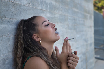 Latin and Hispanic girl, young and nonconformist, rebellious, smoking a cigarette rolled by...