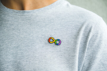 Teenage boy with autism infinity rainbow symbol sign metallic pin brooch on t-shirt. World autism awareness day, autism rights movement, neurodiversity, autistic acceptance movement